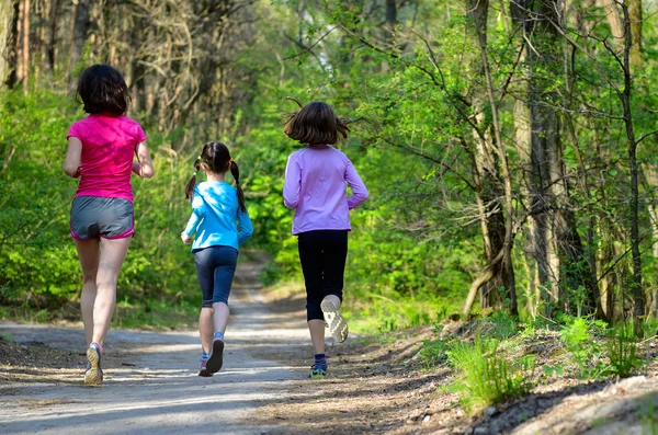 Familiesport, gelukkig actieve moeder en kinderen joggen buiten, die in bos loopt — Stockfoto