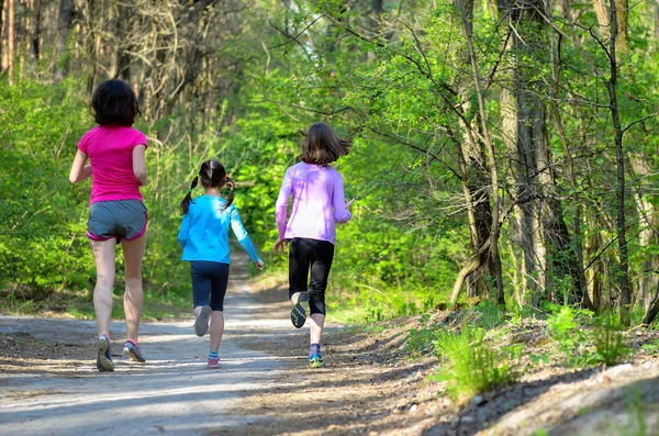 Familjen sport, glada aktiva mor och barn jogga utomhus, med i skogen — Stockfoto