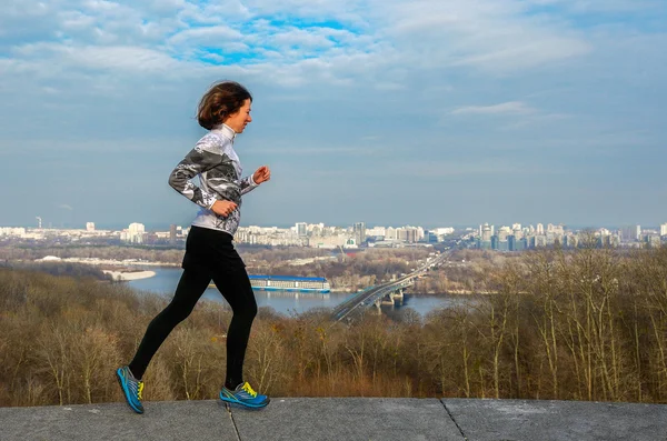 Läuferin joggt mit schönem Blick auf die Stadt, läuft und trainiert im Freien — Stockfoto
