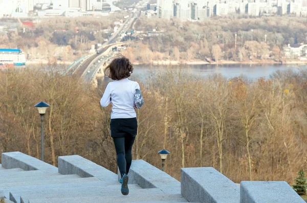 Kobieta lekkoatletka jogging z widokiem na piękne miasto, działa i pracuje się na zewnątrz — Zdjęcie stockowe