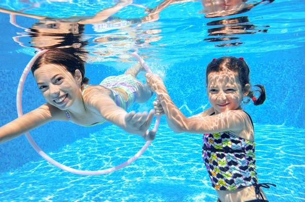 Niños felices nadan en la piscina bajo el agua, niñas nadando, jugando y divirtiéndose, niños deportes acuáticos — Foto de Stock