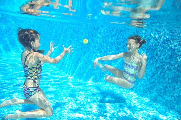 Les enfants heureux nagent dans la piscine sous l'eau, les filles nagent, jouent et s'amusent, les enfants font du sport nautique — Photo