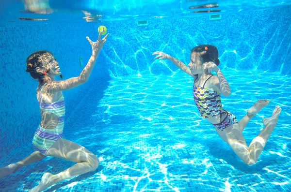 Happy children swim in pool underwater, girls swimming, playing and having fun, kids water sport