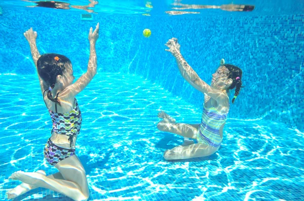 Les enfants heureux nagent dans la piscine sous l'eau, les filles nagent, jouent et s'amusent, les enfants font du sport nautique — Photo