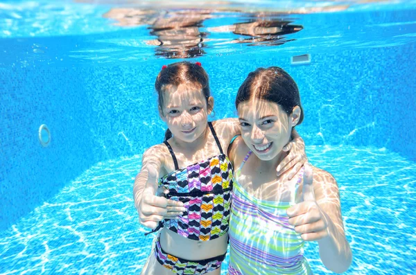 Niños felices nadan en la piscina bajo el agua, niñas nadando, jugando y divirtiéndose, niños deportes acuáticos —  Fotos de Stock