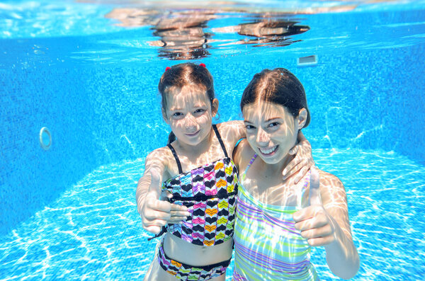 Happy children swim in pool underwater, girls swimming, playing and having fun, kids water sport