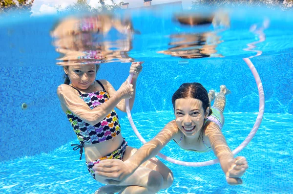 Les enfants heureux nagent dans la piscine sous l'eau, les filles nagent, jouent et s'amusent, les enfants font du sport nautique — Photo