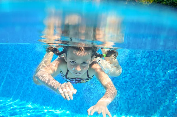 Happy girl swims in pool underwater, active kid swimming, playing and having fun, children water sport