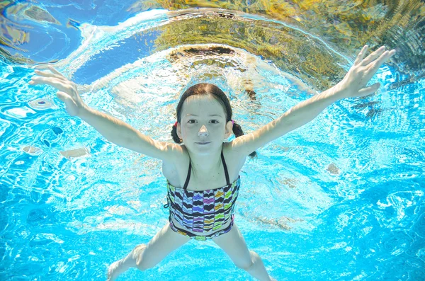 Child swims in pool underwater, happy active girl has fun in water, kid sport on family vacation — Stock Photo, Image