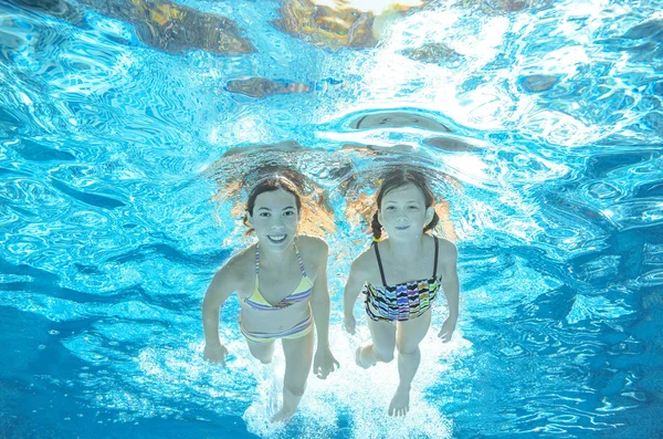 Crianças nadam na piscina subaquática, meninas ativas felizes se divertir na água, crianças esporte em férias em família — Fotografia de Stock