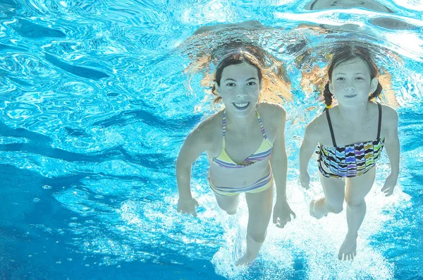 Crianças nadam na piscina subaquática, meninas ativas felizes se divertir na água, crianças esporte em férias em família — Fotografia de Stock