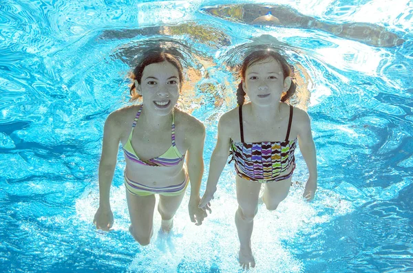 Crianças nadam na piscina subaquática, meninas ativas felizes se divertir na água, crianças esporte em férias em família — Fotografia de Stock