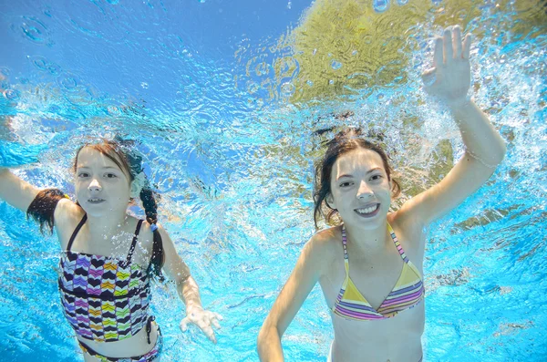 Crianças nadam na piscina subaquática, meninas ativas felizes se divertir na água, crianças esporte em férias em família — Fotografia de Stock