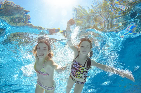 Children swim in pool underwater, happy active girls have fun in water, kids sport on family vacation — Stock Photo, Image