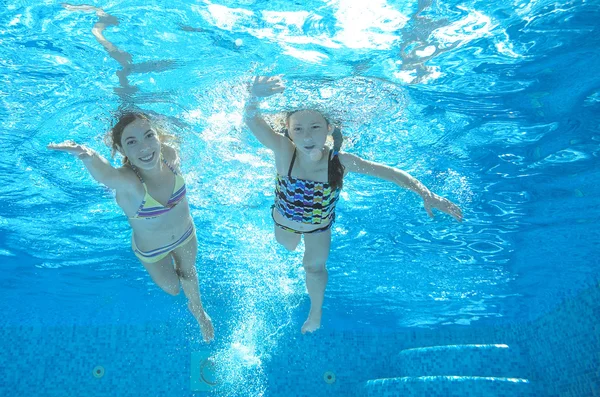 I bambini nuotano in piscina sott'acqua, le ragazze attive felici si divertono in acqua — Foto Stock