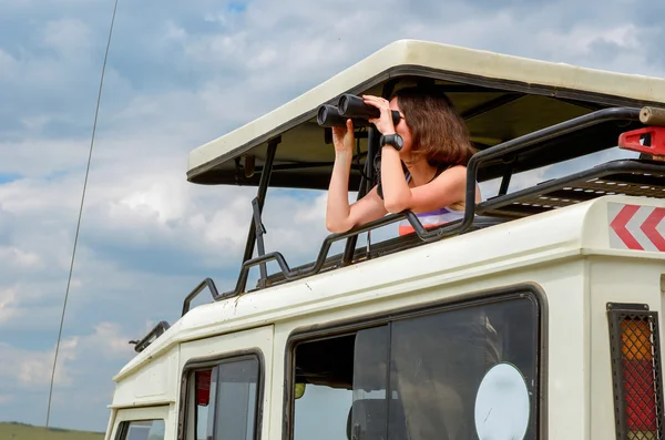 Woman tourist on safari in Africa, travel in Kenya, watching wildlife in savanna with binoculars — Stock Photo, Image