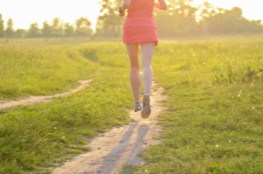 Bulanık arka plan: gün batımı veya gündoğumu, spor ve fitness kavramı kırsal yolda çalışan kadın runner
