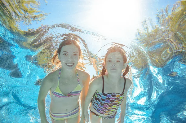 Les enfants nagent dans la piscine ou la mer sous l'eau, les filles actives heureuses s'amusent dans l'eau, les enfants font du sport en vacances en famille — Photo