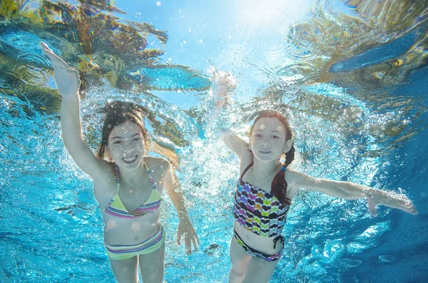 Children swim in pool or sea underwater, happy active girls have fun in water, kids sport on family vacation