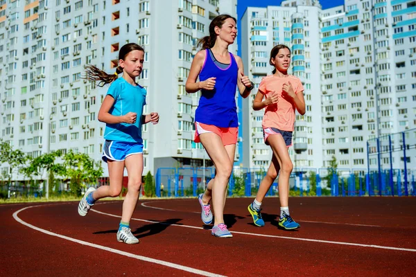 Sport rodzinny, szczęśliwy aktywne matki i dzieci jogging na torze, działa i pracuje na stadionie w nowoczesne miasto — Zdjęcie stockowe