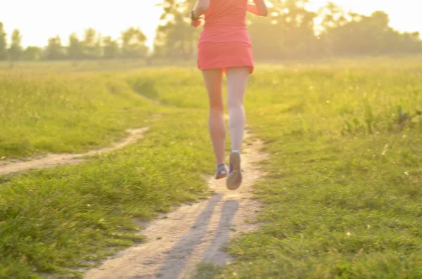 Unscharfer Hintergrund: Läuferin läuft bei Sonnenuntergang oder Sonnenaufgang auf Landstraße, Sport- und Fitnesskonzept — Stockfoto