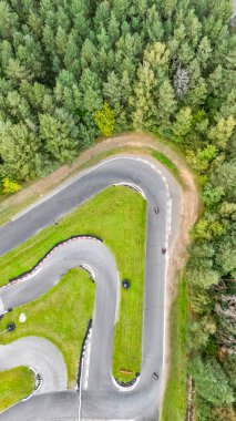 Yeşil ormandaki karting yarış pistinin hava aracı görüntüsü go-kart yarışı arabaları sürüş, kart yarışı açık tekerlek motorsporu, dikey görüntü