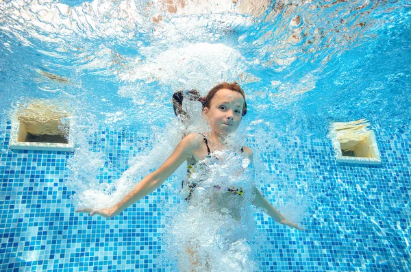 Menina pula e nada na piscina subaquática, criança ativa feliz se diverte na água, esporte infantil em férias em família — Fotografia de Stock