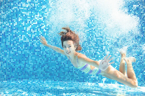 Girl jumps and swims in pool underwater, happy active child has fun in water, kid sport on family vacation