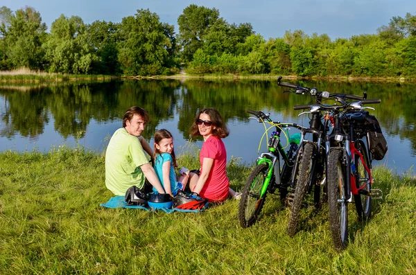 Familjen cykel rida utomhus, aktiva föräldrar och kid cykling och avkopplande nära vackra floden — Stockfoto