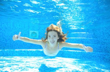 Child swims in pool underwater, happy active girl in goggles has fun under water, kid sport on family vacation