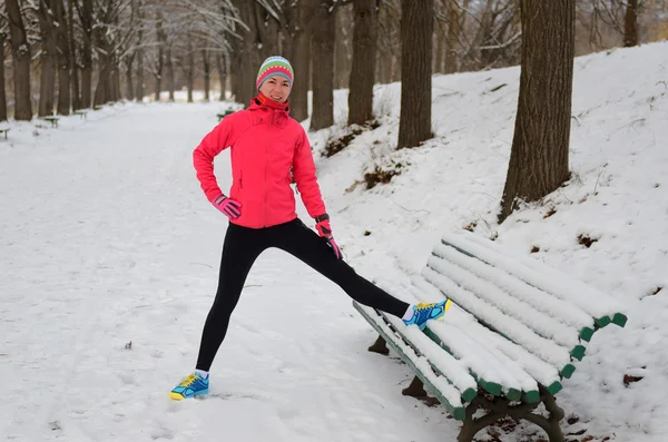 Zimní běh v parku: šťastná žena běžec zahřívání a výkonu než běhání ve sněhu, venkovní sport a fitness koncept — Stock fotografie