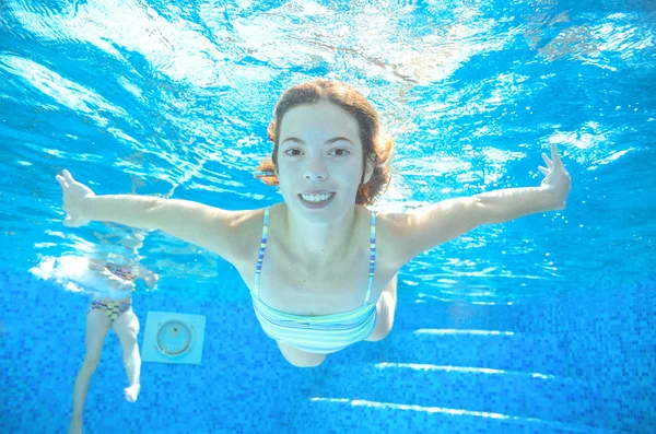 Child swims in pool underwater, happy active girl in goggles has fun under water, kid sport on family vacation — 图库照片