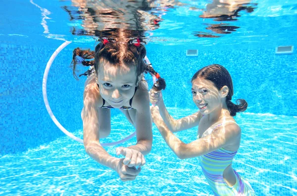 Los niños nadan en la piscina bajo el agua, las niñas activas felices se divierten bajo el agua, los niños se divierten en vacaciones familiares — Foto de Stock