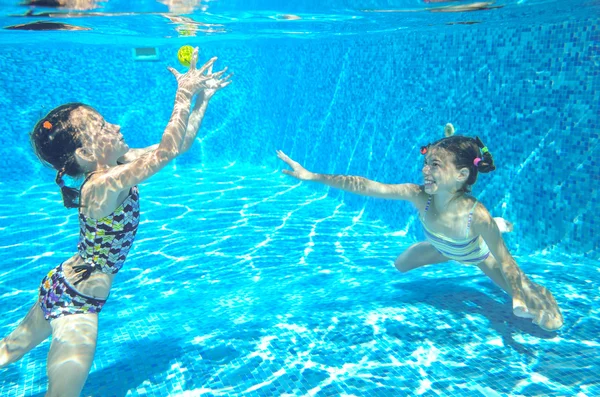Niños activos felices nadan en la piscina y juegan bajo el agua, chicas buceando y divirtiéndose, niños en vacaciones de verano, concepto deportivo —  Fotos de Stock