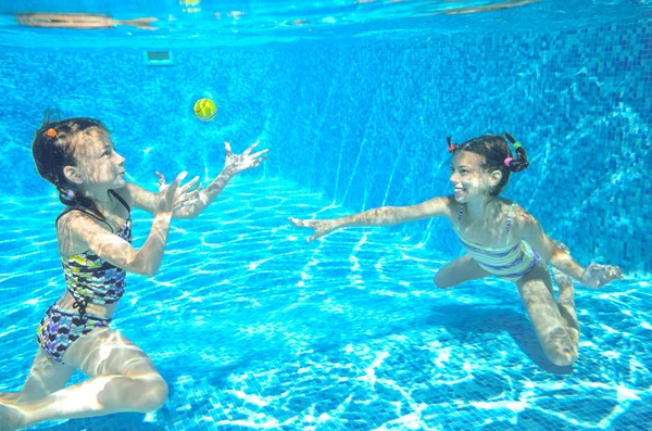 Šťastné aktivní děti plavat v bazénu a hrát pod vodou, holky, potápění a baví, děti na letní dovolenou, sport koncept — Stock fotografie