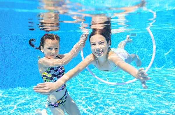 Los niños nadan en la piscina bajo el agua, las niñas activas felices se divierten bajo el agua, los niños se divierten en vacaciones familiares — Foto de Stock