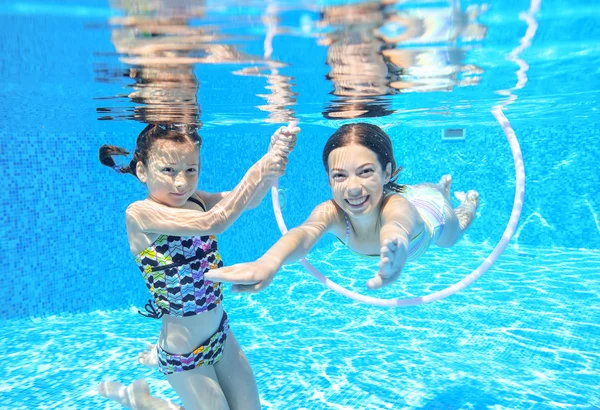 Children swim in pool underwater, happy active girls have fun under water, kids sport on family vacation