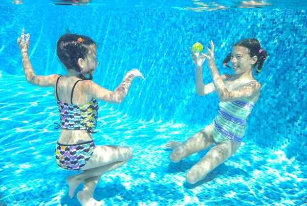 Children swim in pool underwater, happy active girls have fun under water, kids sport on family vacation — Stock Photo, Image