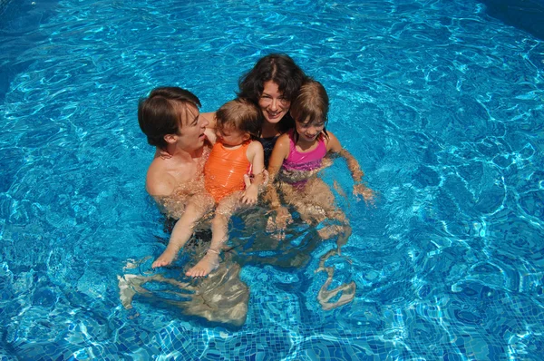 Familia feliz divirtiéndose en la piscina en las vacaciones de verano — Foto de Stock