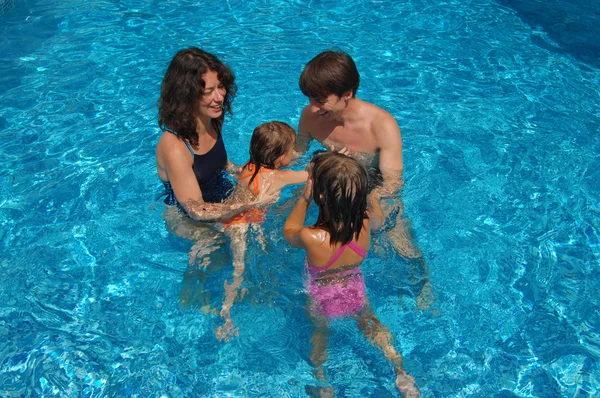 Familia feliz divirtiéndose en la piscina en las vacaciones de verano — Foto de Stock