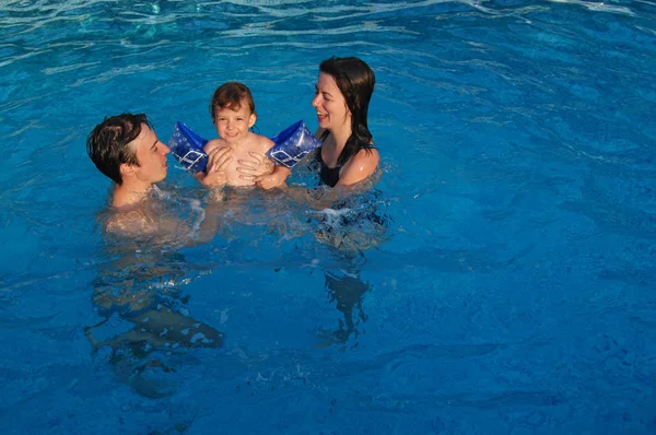 Familie med barn have det sjovt i swimmingpoolen - Stock-foto