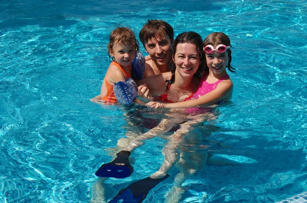 Glad familie har det sjovt i swimmingpool på sommerferie - Stock-foto