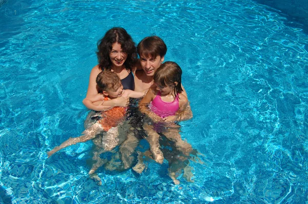 Lyckliga familjen ha roligt i poolen på sommarlovet — Stockfoto
