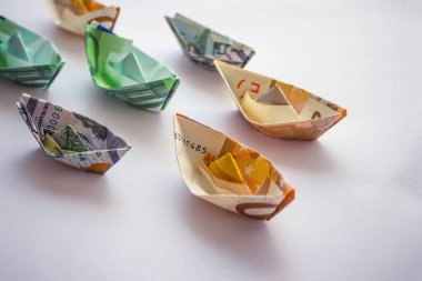 Banknotlar gemi şeklinde toplandı. Nakliye ve seyahat şirketlerinin geliri ve giderleri. Hafif arkaplan, vignetting.