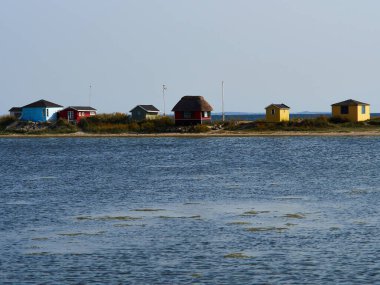 Güzel, küçük ahşap yazlık kulübeler, parlak renklerle boyanmış açık mavi deniz, Aero Adası, Güney Funen, Danimarka - büyük bir turistik dönüm noktası