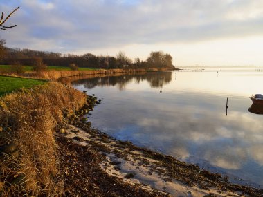 Deniz kıyısında büyük bulutlar oluşmuş, berrak, sakin su günbatımı ile büyüleyici bir huzur Funen Danimarka