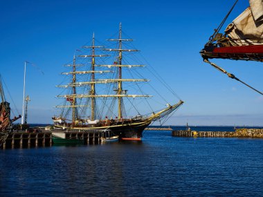 Klasik tasarım. Uzun gemi bir limana giriyor. Büyük deniz arka planı resmi.