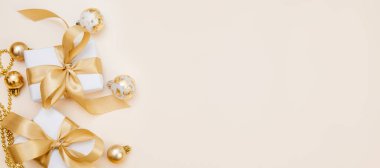 Beyaz hediyeler, altın fiyonklar ve bej arka planda ışıldayan süslemelerle süslü bir kış düzeni. Tebrik kartları, web pankartları ya da markalar için mükemmel.