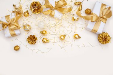 Altın Noel dairesi zarif hediyeler, çam kozalakları ve bej yüzeyinde ip ışıkları ile yatıyordu. Web tasarımı, reklamcılık veya kutlama amaçlı selamlama düzenleri için uygun kopya alanı olan rahat kompozisyon.