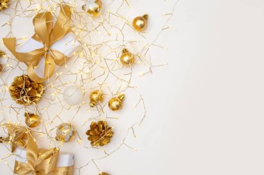 Altın Noel dairesi zarif hediyeler, çam kozalakları ve bej yüzeyinde ip ışıkları ile yatıyordu. Web tasarımı, reklamcılık veya kutlama amaçlı selamlama düzenleri için uygun kopya alanı olan rahat kompozisyon.